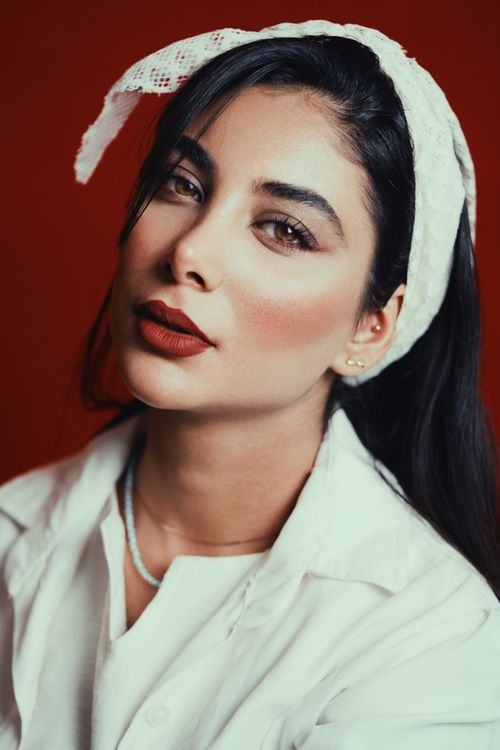 Free Elegant woman in white attire with red lipstick against a red background, exuding sophistication. Stock Photo