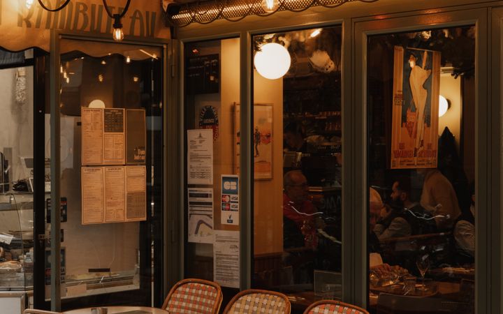 Paris bistro with outdoor seating, warm string lights, and cozy ambiance in the evening.