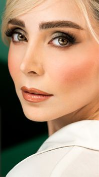 Close-up portrait of a woman with striking makeup and styled blonde hair, highlighting eyes.