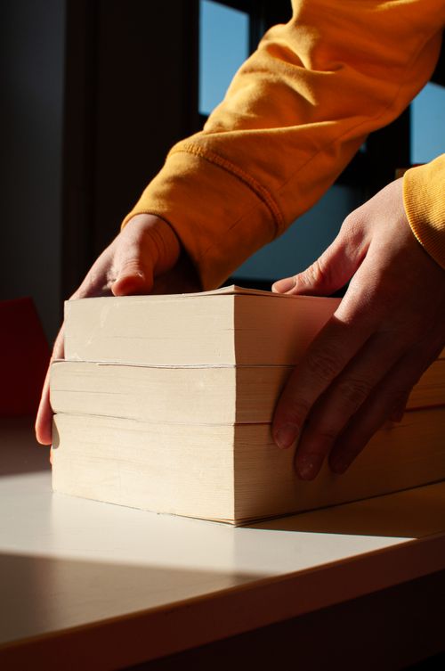 Free Hands arranging books on a table in sunny Milano, perfect for reading enthusiasts. Stock Photo