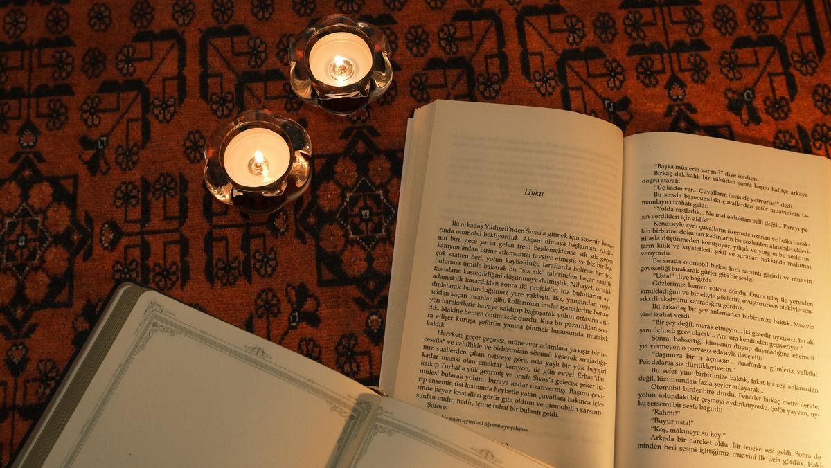 Five gold rings arranged on an open vintage carol book page in warm candlelight.