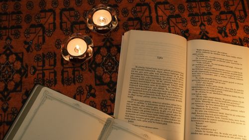 Free Open book with candles on a patterned rug creating a warm, cozy ambiance. Stock Photo