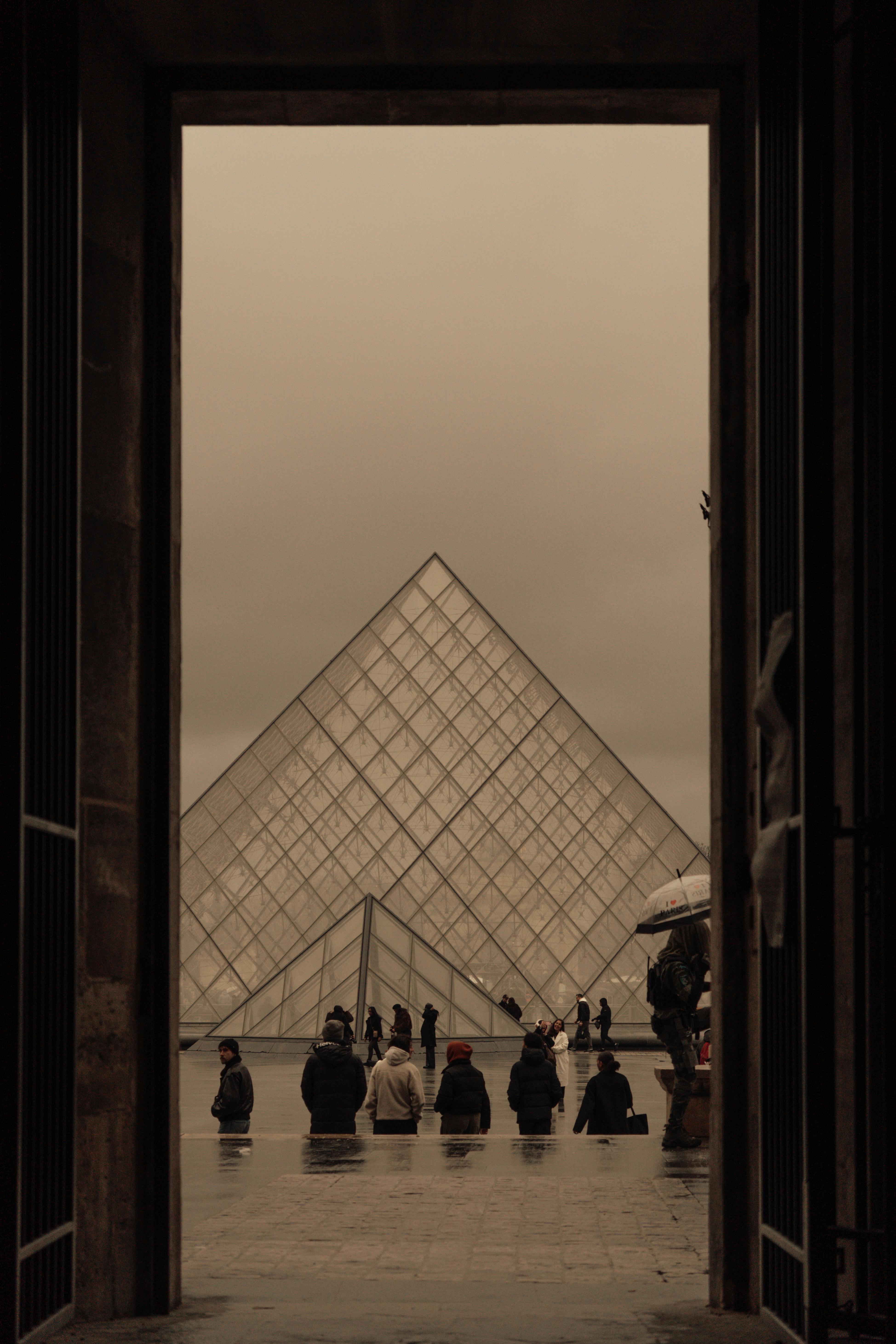 ingyenes A párizsi Louvre-piramis keretezett látképe egy esős napon, amely megragadja a modern és a történelmi építészeti kontrasztot. Stockfotó