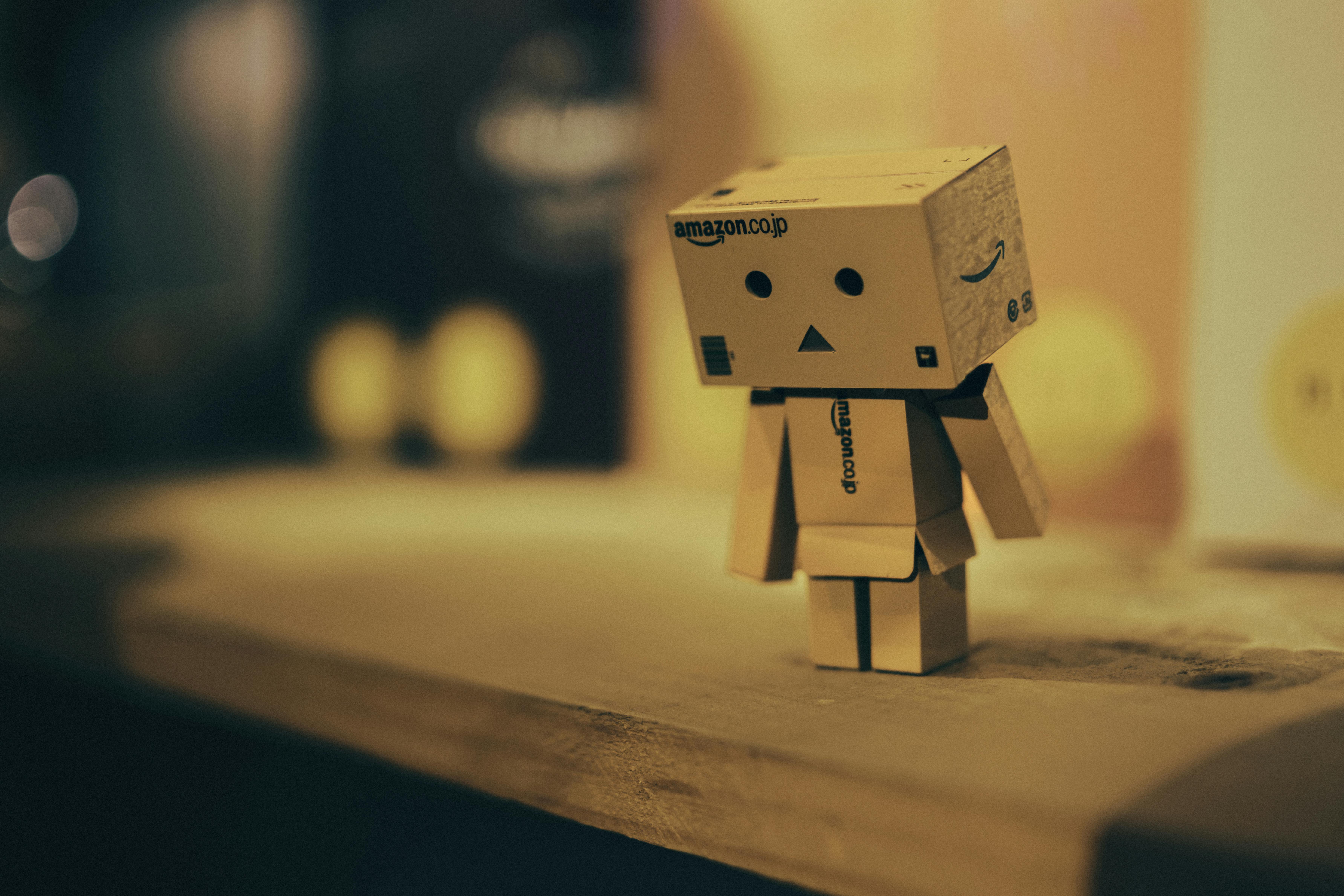 Miễn phí Một mô hình robot nhỏ bằng bìa cứng đặt trên kệ gỗ trong một căn phòng có ánh sáng ấm áp. Ảnh lưu trữ