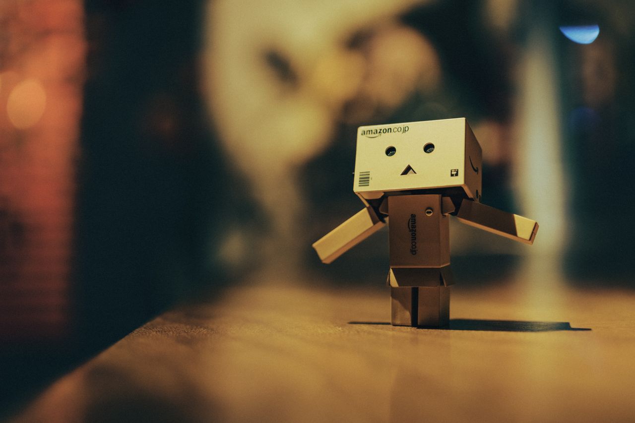 cardboard toy robot standing on a wooden surface with warm bokeh light