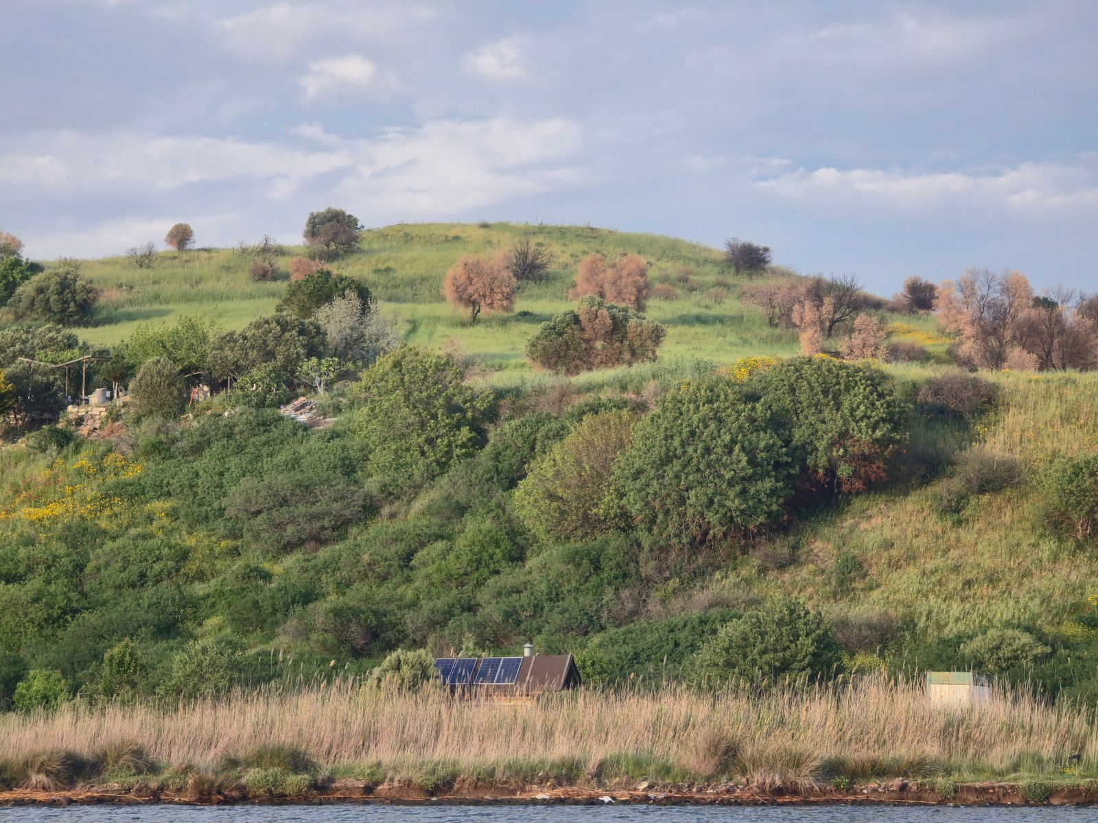 Hillside home with solar panels beside the water (illustrative photo)