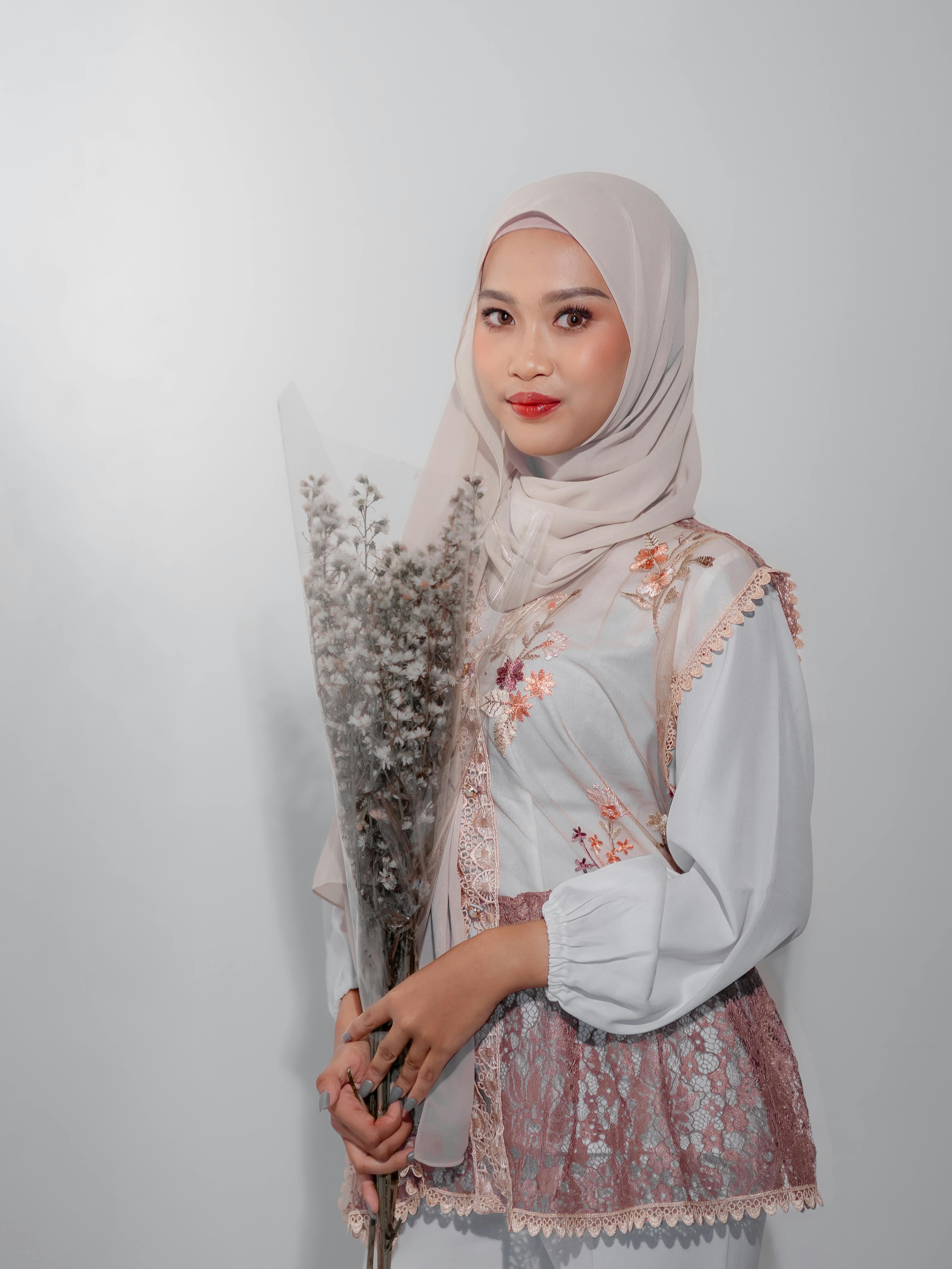 Gratis Ritratto di una donna con un abito floreale che tiene in mano fiori secchi, emanando eleganza. Foto a disposizione