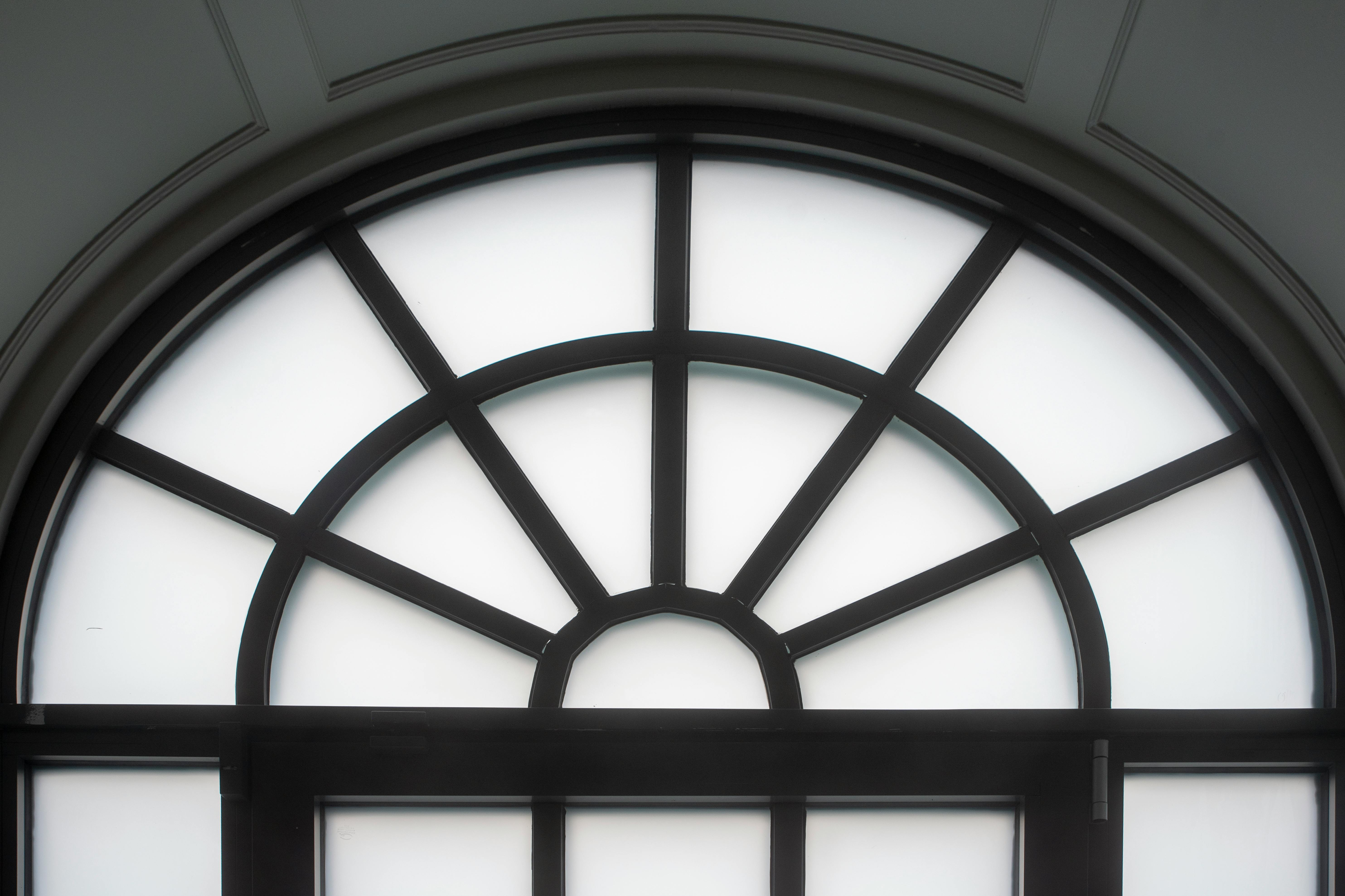 Gratis Elegant buet vindu med klassisk svart ramme og hvitt frostet glass, innendørsbelysning. Arkivbilde