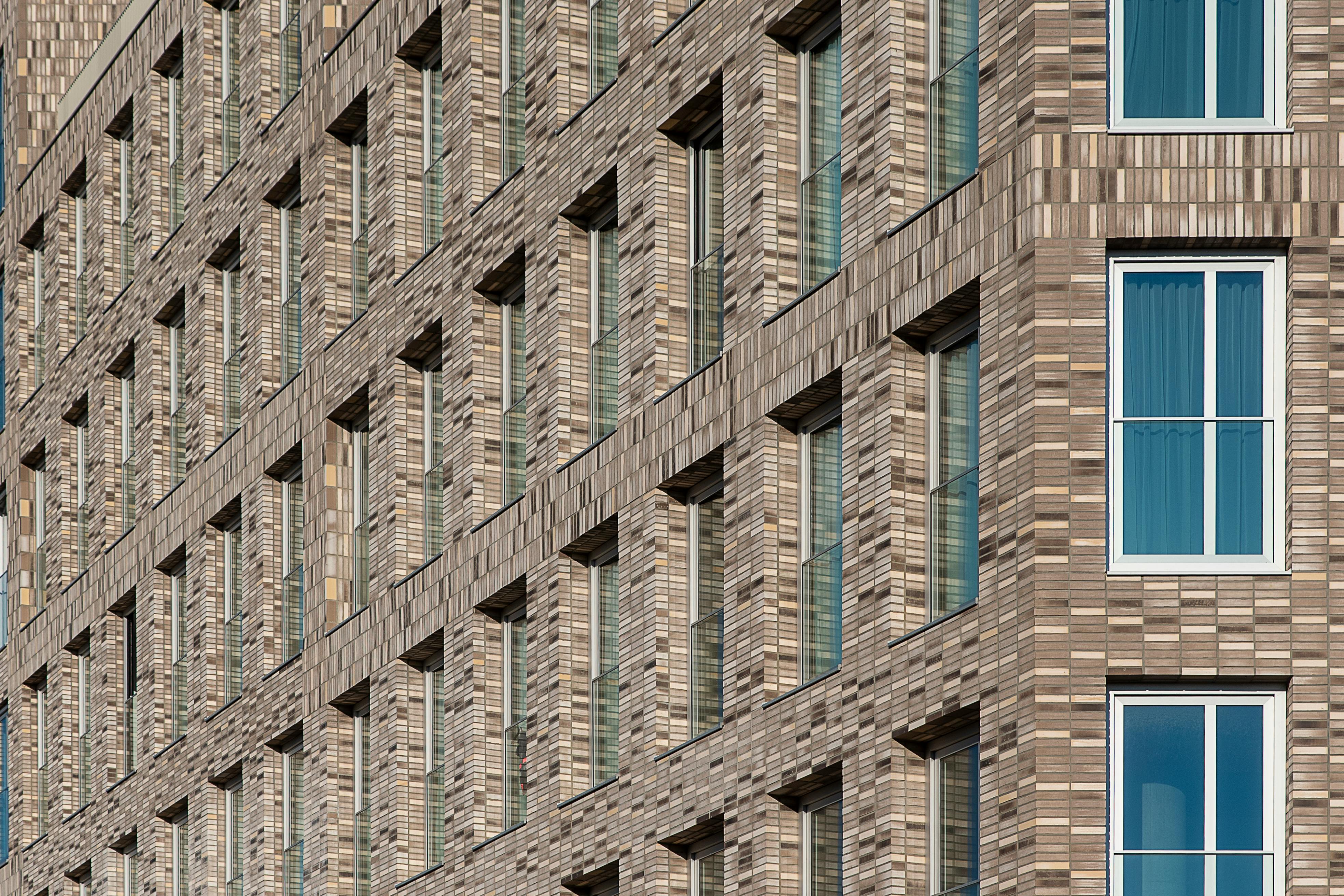Gratis Primo piano di un moderno edificio in mattoni che mette in mostra motivi simmetrici delle finestre e intricati dettagli architettonici. Foto a disposizione