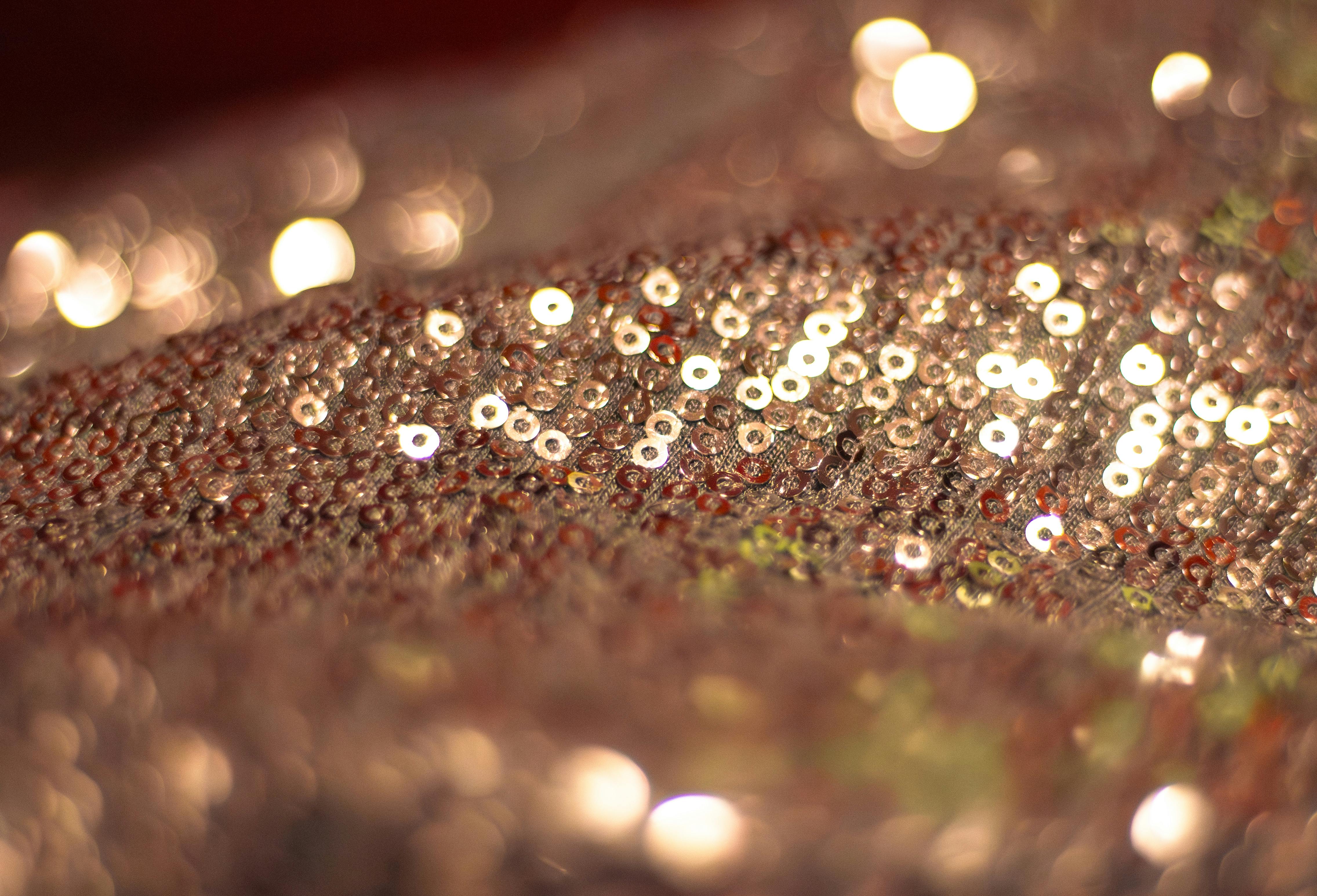 Gratis Primo piano di un tessuto di paillettes scintillanti che crea uno splendido effetto bokeh in calde tonalità dorate. Foto a disposizione
