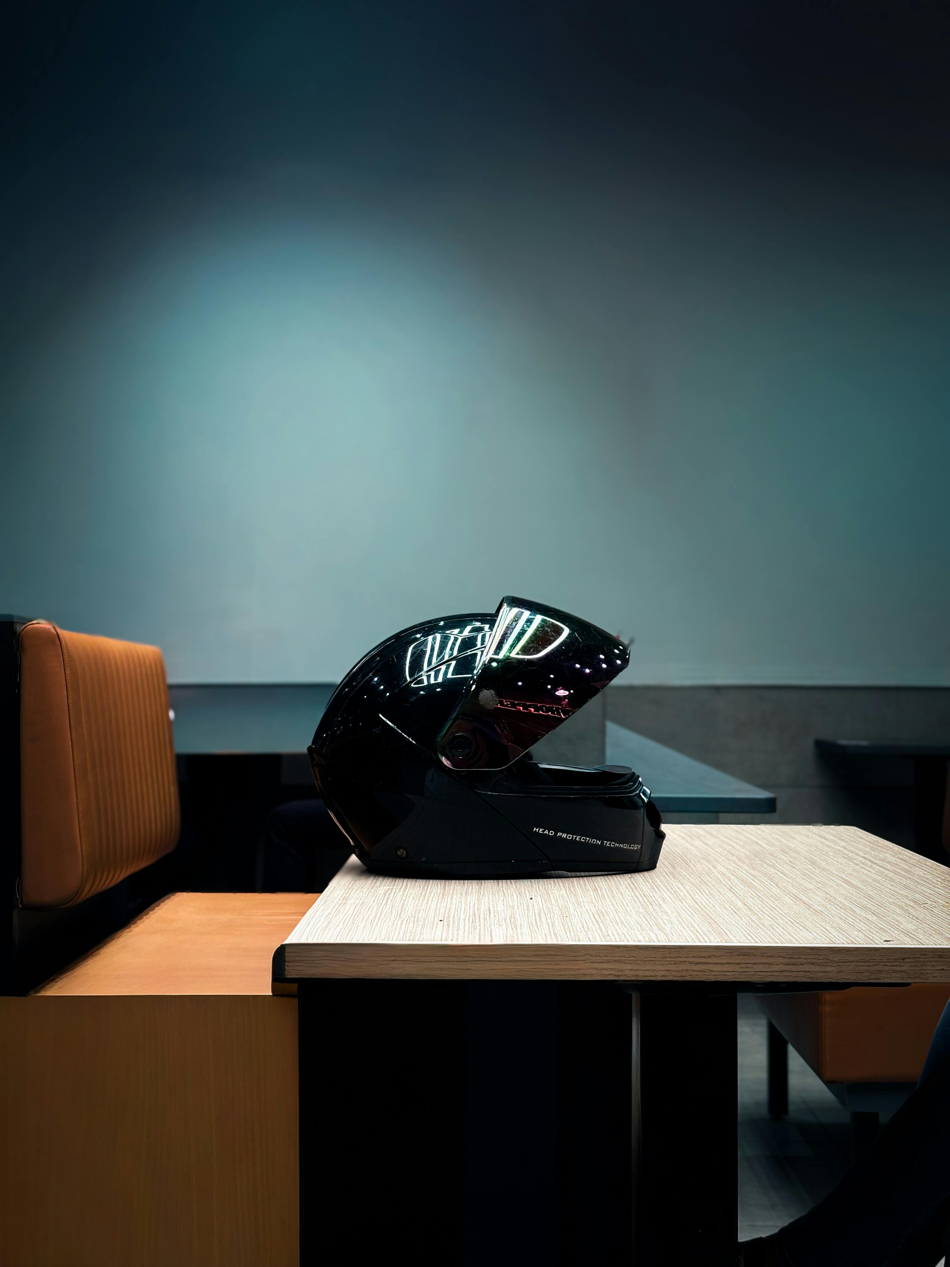 Miễn phí Một chiếc mũ bảo hiểm xe máy màu đen bóng bẩy được đặt trên bàn trong một không gian nội thất trang nhã. Ảnh lưu trữ