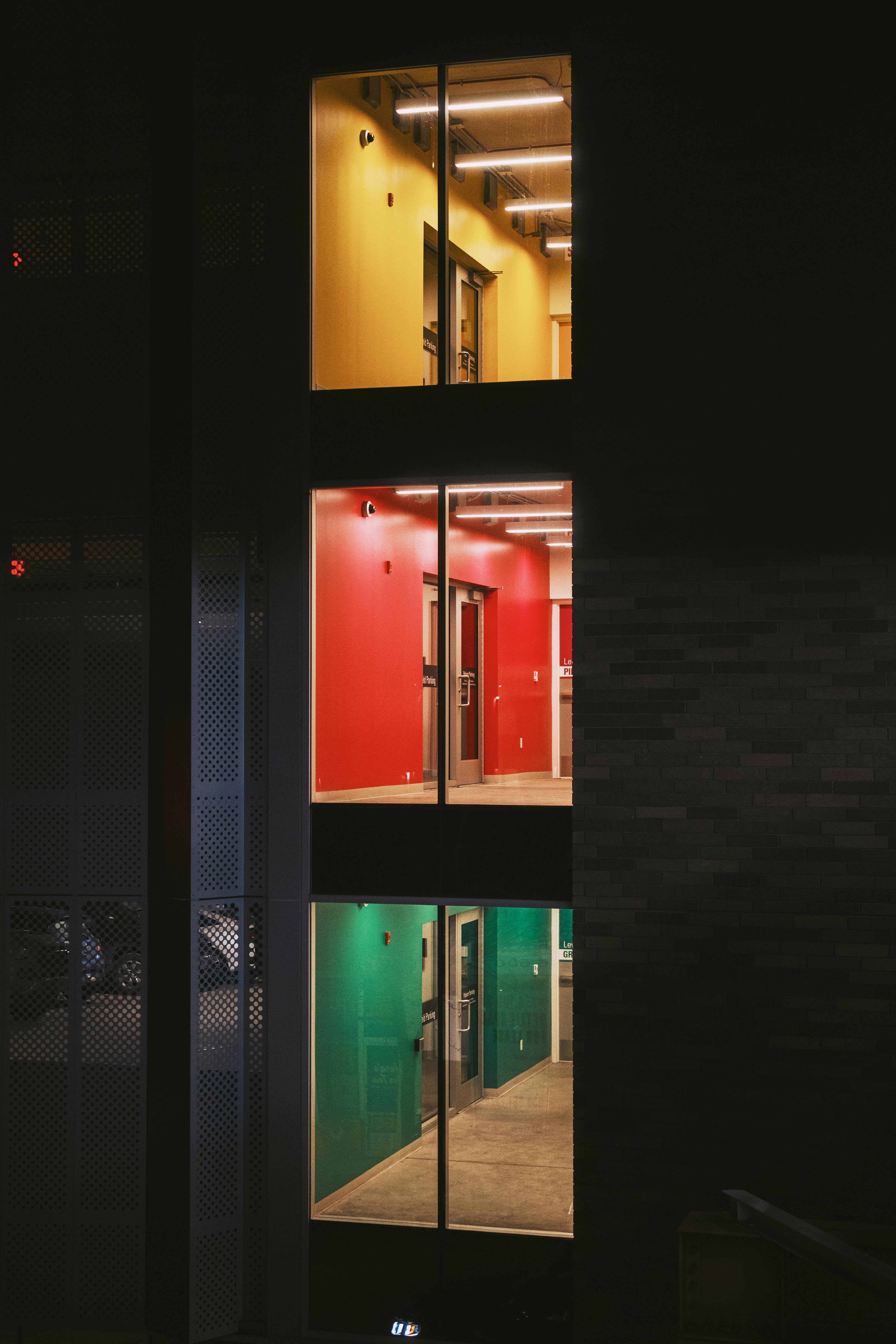 Free Vibrant view of a building interior at night with yellow, red, and green rooms on different floors. Stock Photo