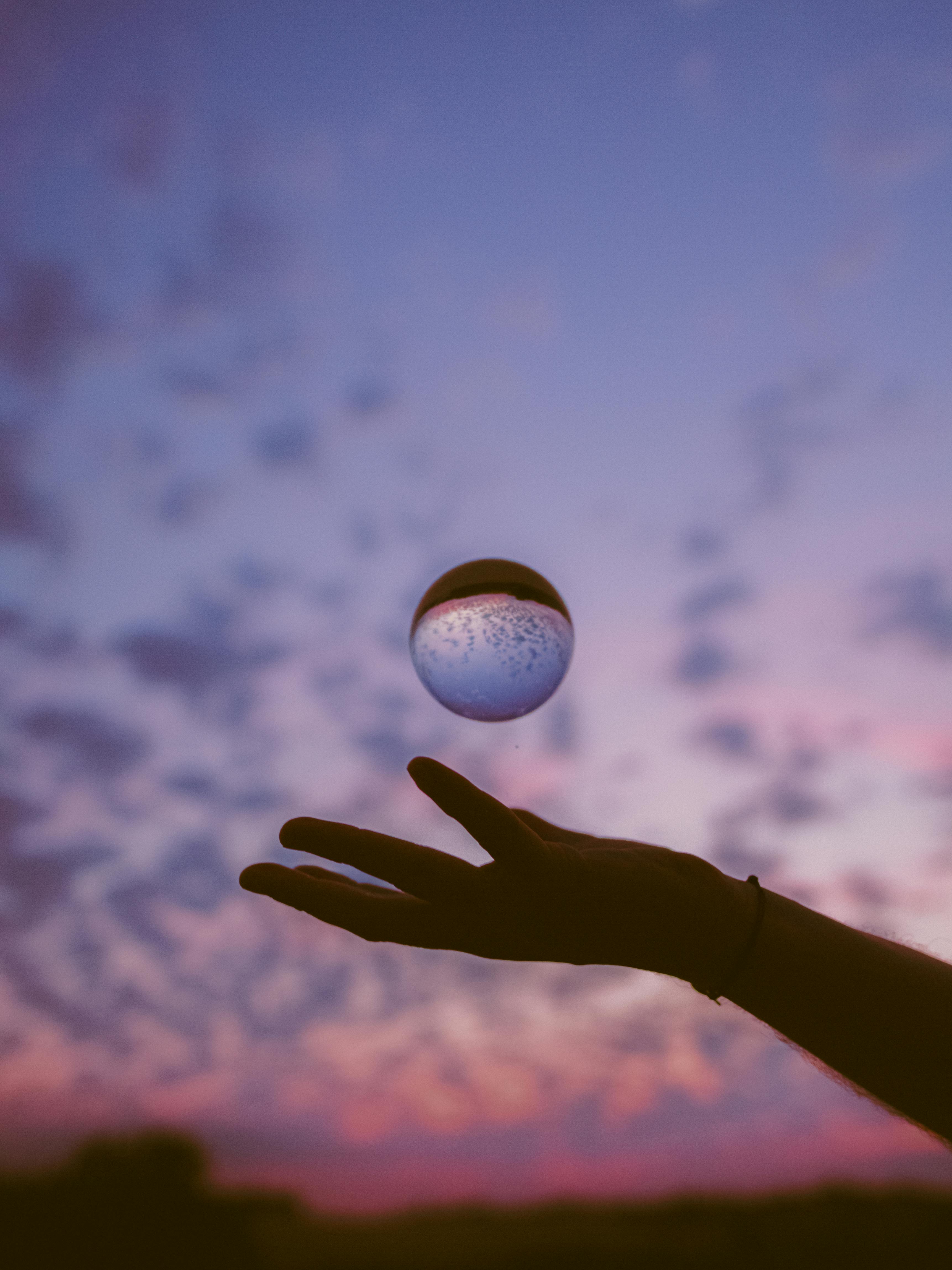 ingyenes Egy kéz egy fényvisszaverő gömböt tart az élénk lila alkonyati égbolt előtt Toulouse-ban, Franciaországban. Stockfotó