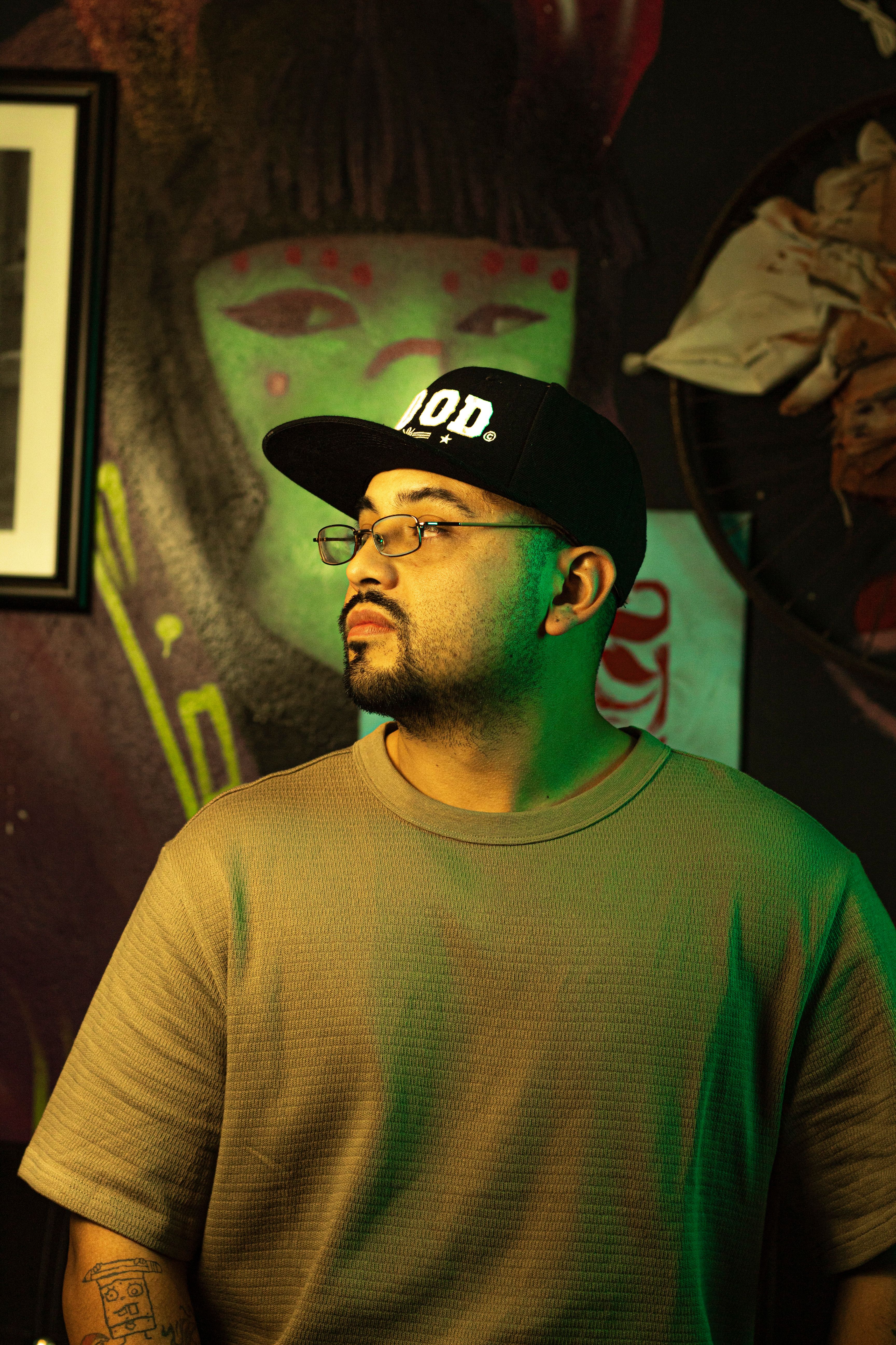 Man in a cap and glasses posing against a vibrant urban mural in Mexico.