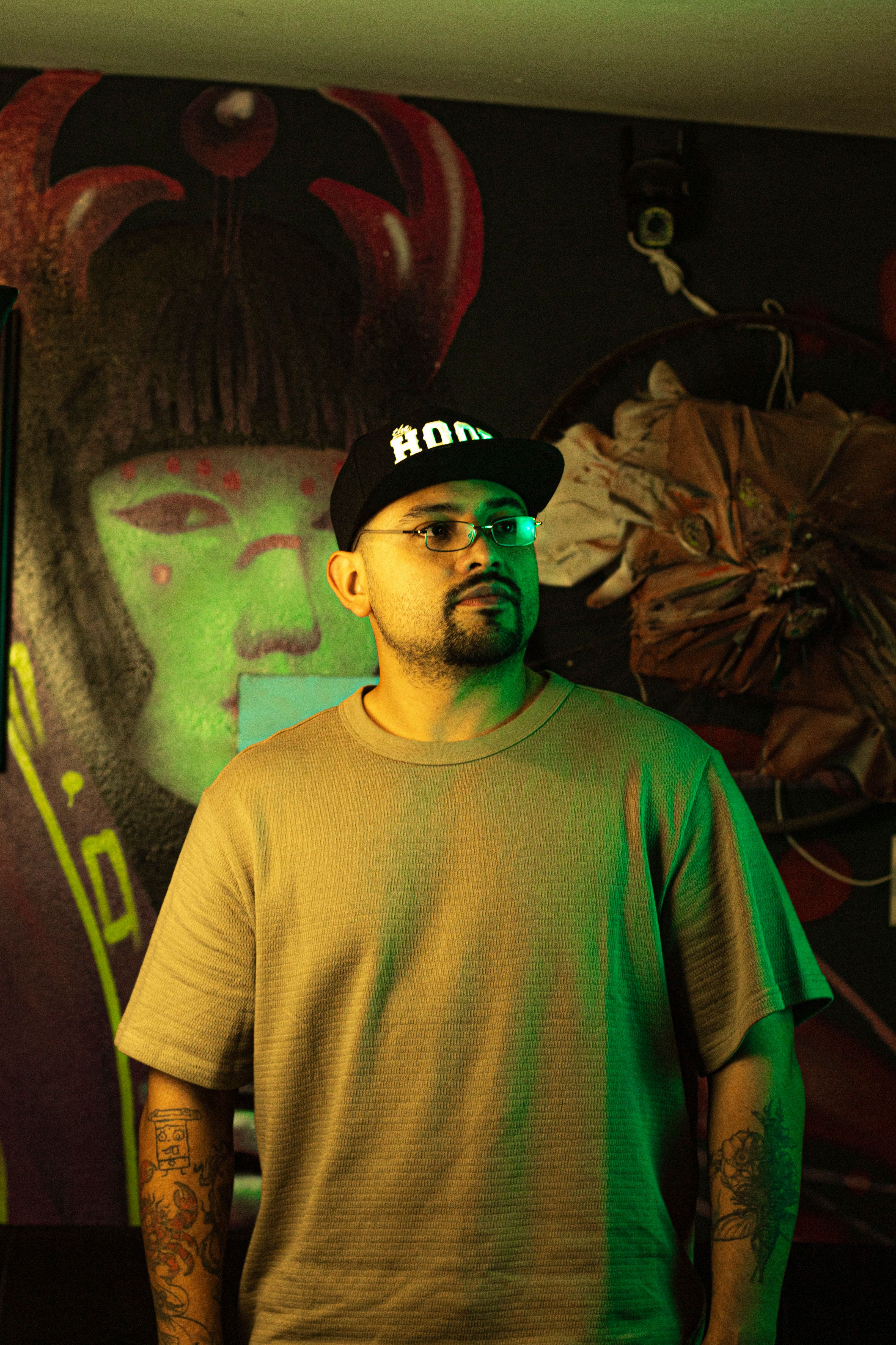 Man in urban setting with graffiti backdrop, highlighting modern street culture.