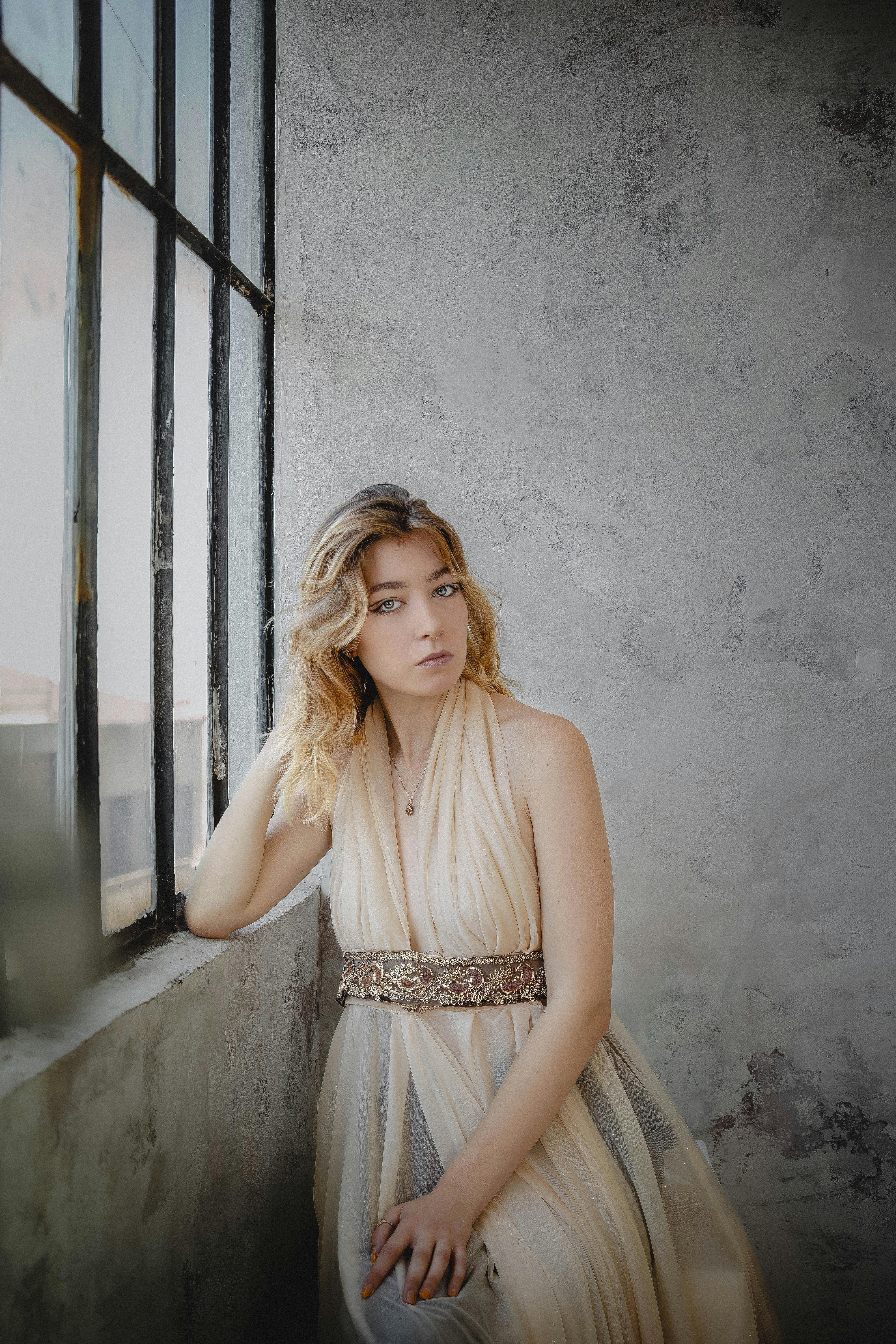 ingyenes Elegáns nő lenge ruhában ül egy napsütötte ipari ablaknál Isztambulban. Stockfotó