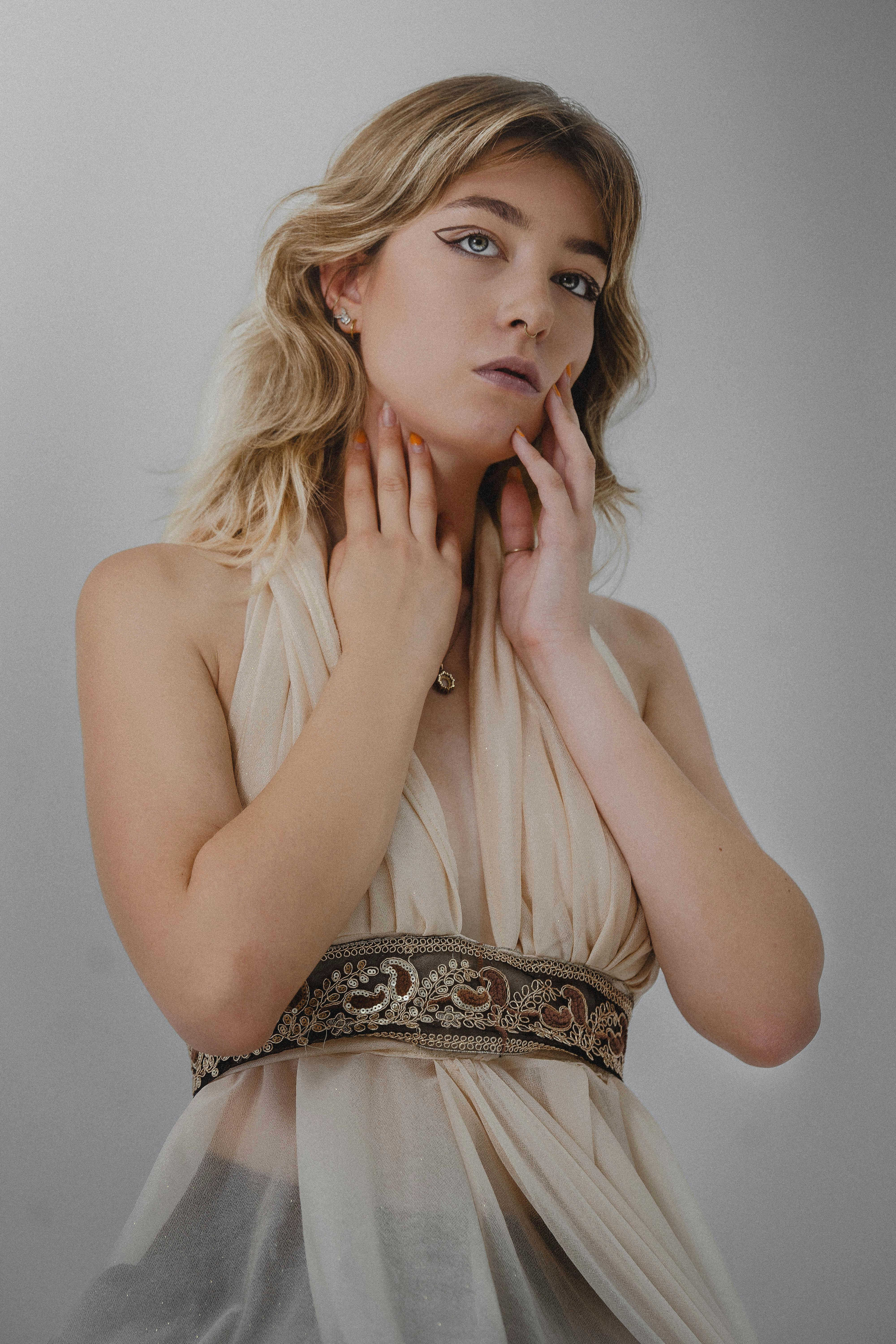 Miễn phí Một người phụ nữ thanh lịch tạo dáng duyên dáng trong chiếc váy màu kem với những chi tiết tinh tế. Ảnh lưu trữ