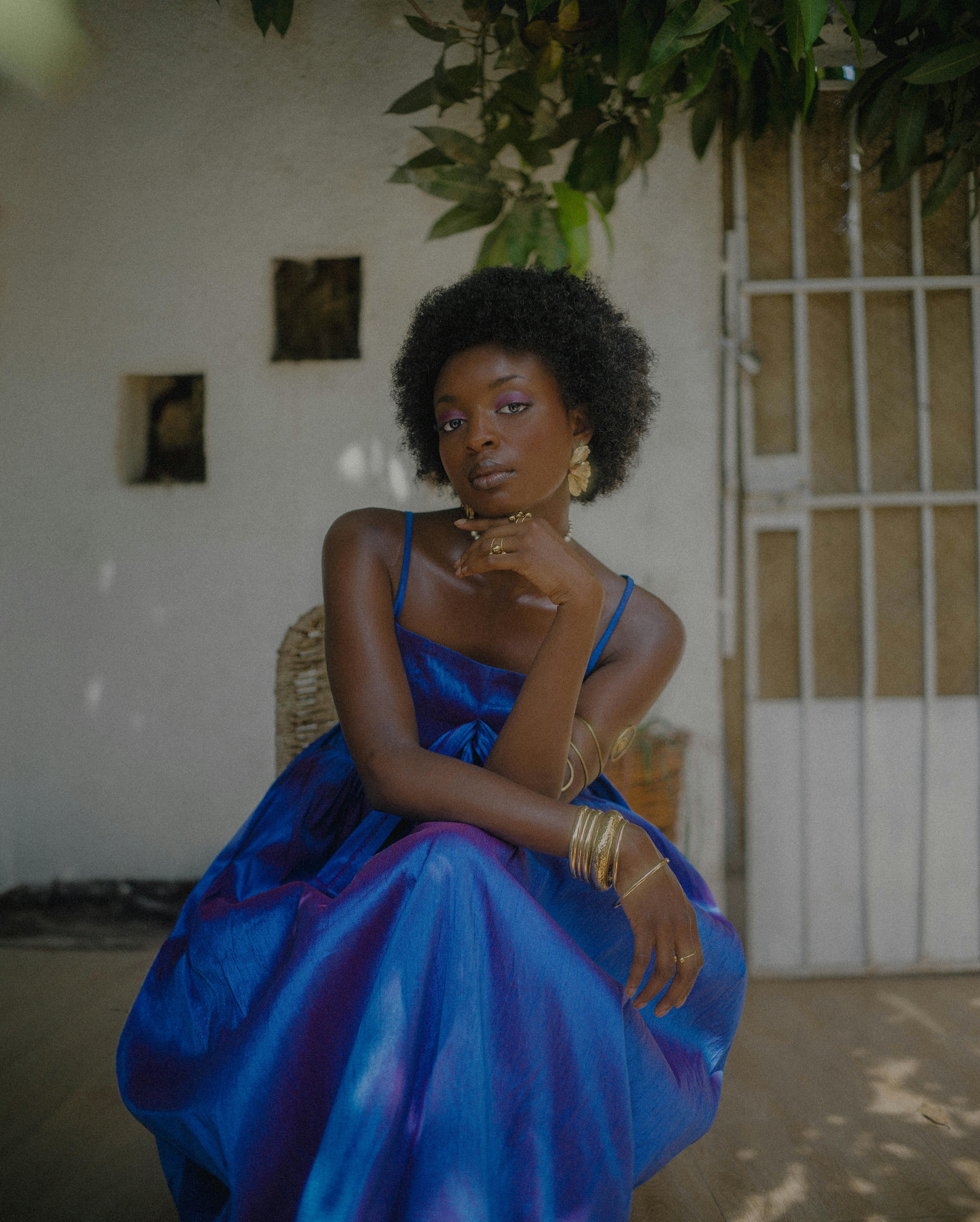 Stylish portrait of a woman in a blue dress sitting gracefully outdoors in Abuja, Nigeria.