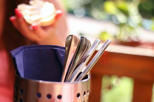Close-up of stainless steel cutlery in a holder during an outdoor dining setting.
