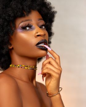 Striking portrait of a woman with afro hairstyle and bold makeup, showcasing fashion and beauty.