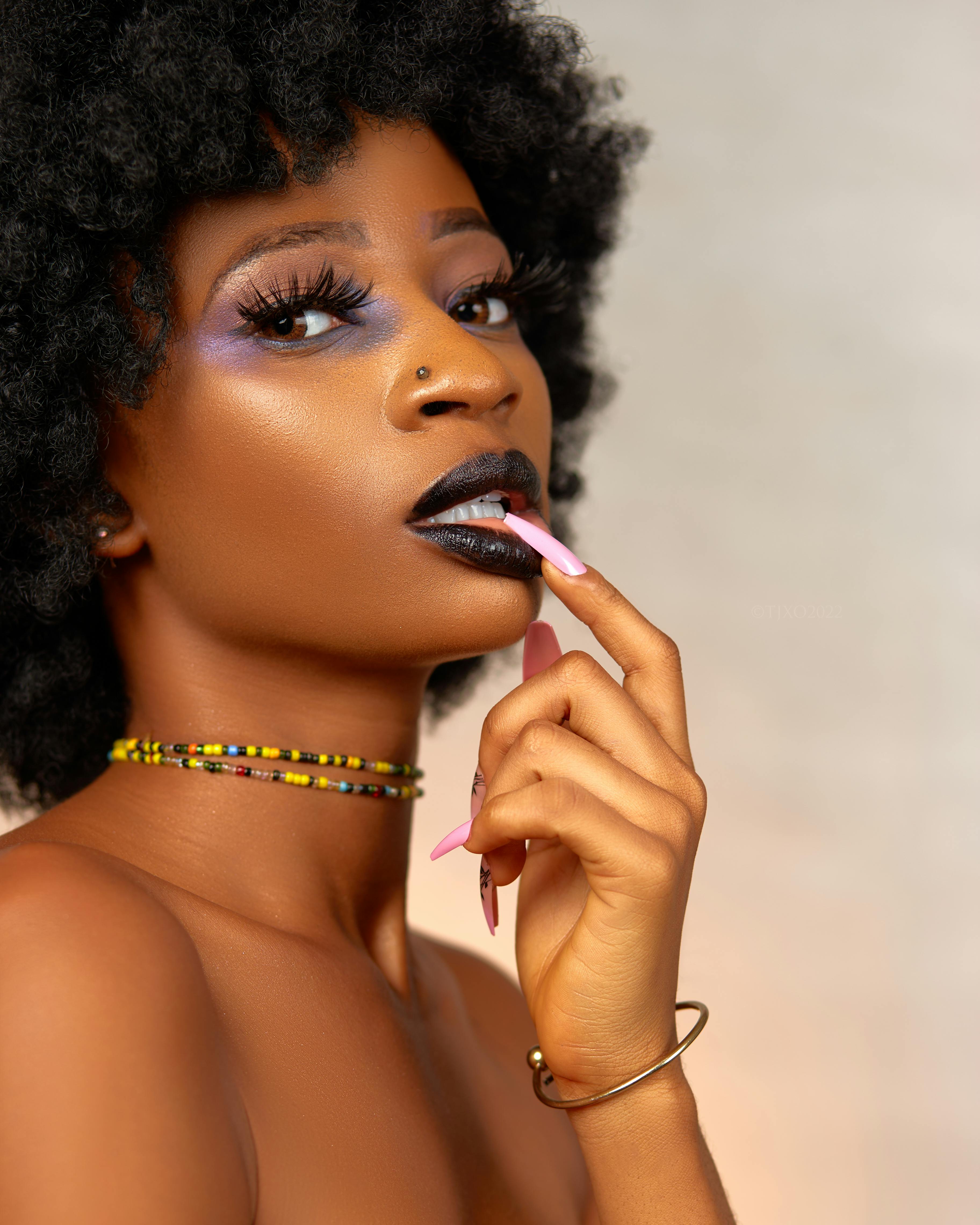 Gratis Splendido ritratto di una donna con acconciatura afro e trucco audace, che mette in mostra moda e bellezza. Foto a disposizione