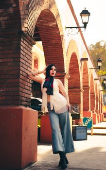 Stylish woman posing by urban arches in casual attire, capturing modern fashion.