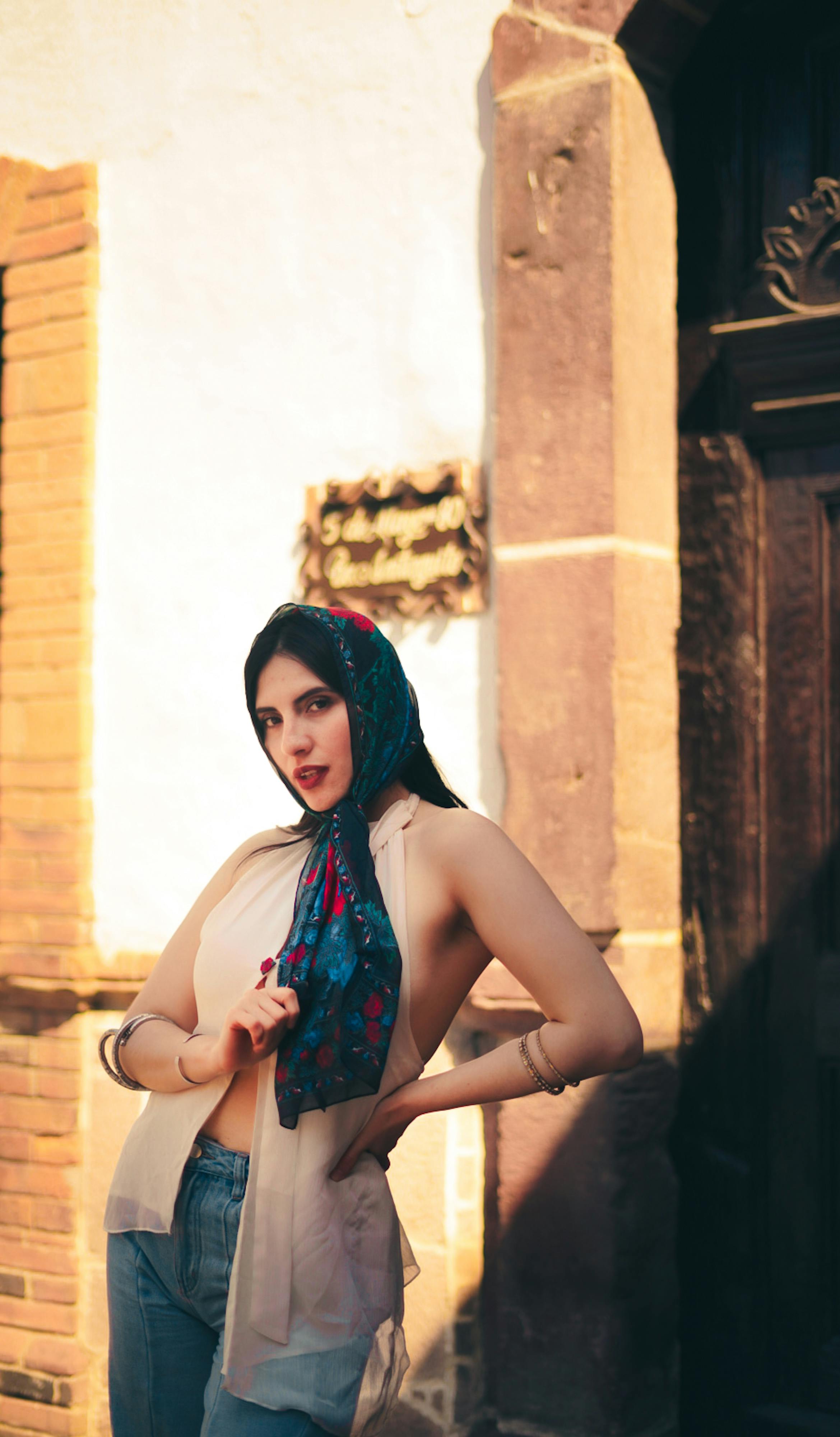 Δωρεάν Κομψή γυναίκα με πολύχρωμη μαντίλα ποζάρει με αυτοπεποίθηση στο φως του ήλιου, επιδεικνύοντας αστικό στυλ. Φωτογραφία από στοκ φωτογραφιών