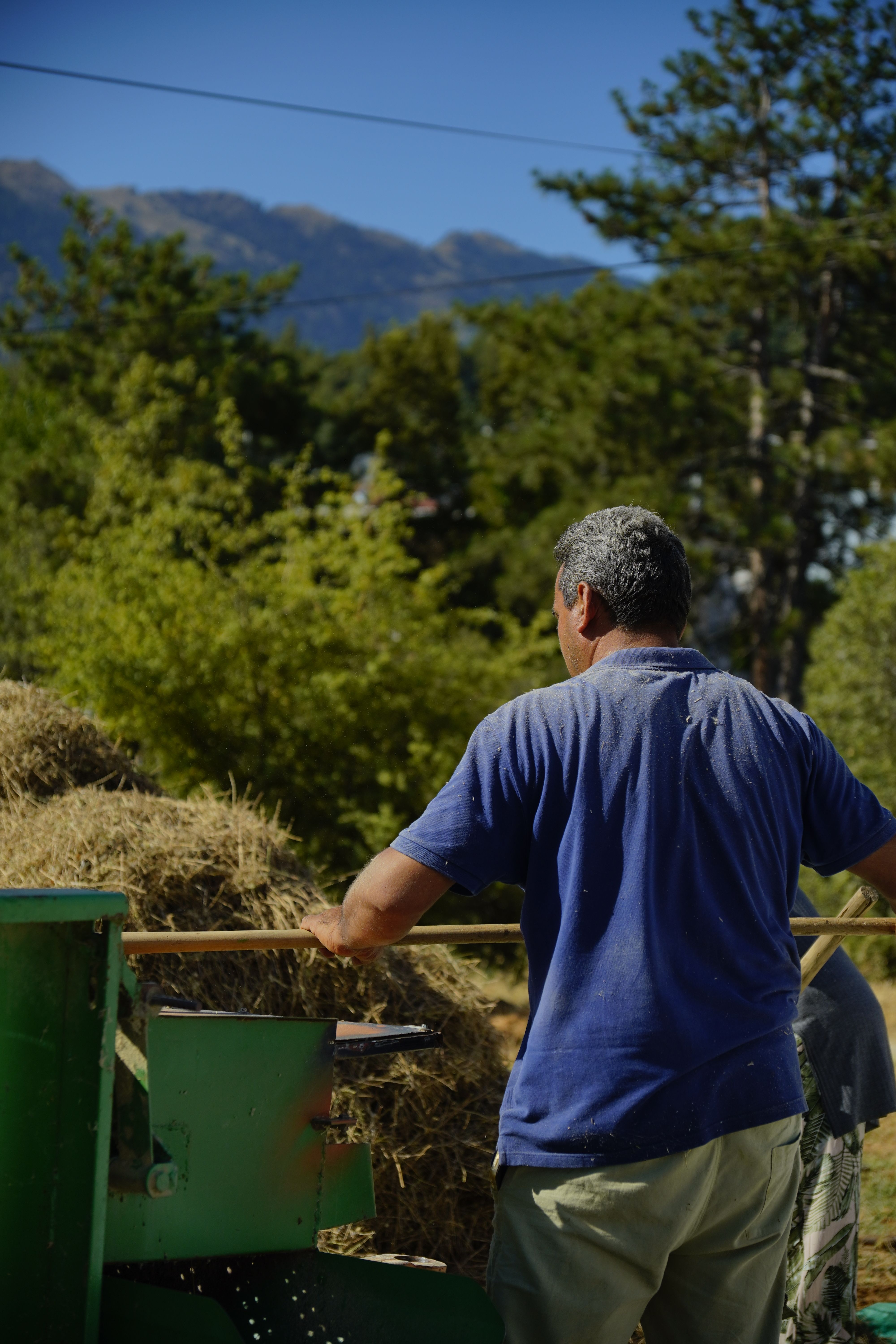 A man working with hay under a bright summer sky in rural Türkiye, showcasing agricultural life.
