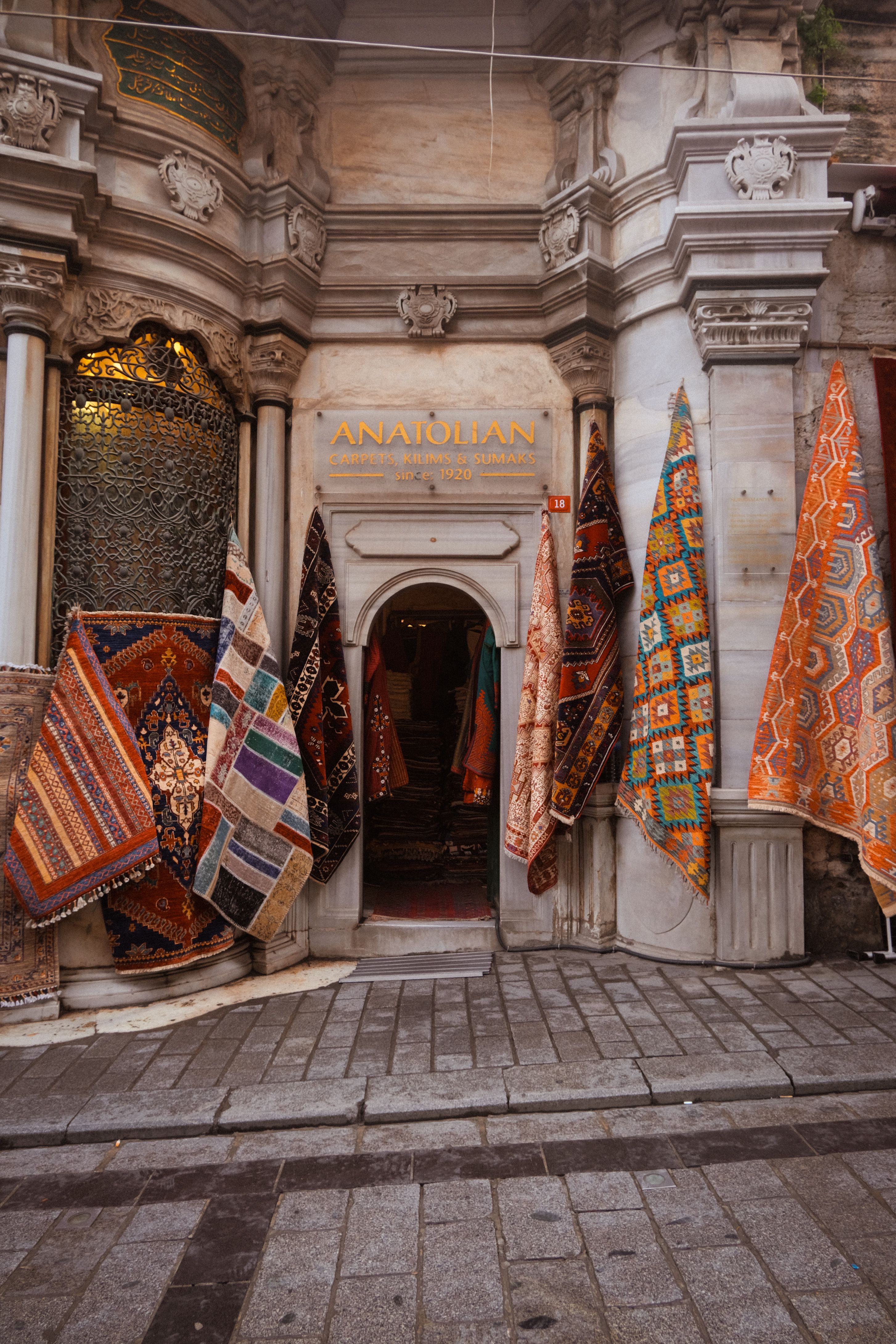 Vibrant Turkish carpets adorn an Istanbul shop entrance, showcasing traditional Anatolian designs.