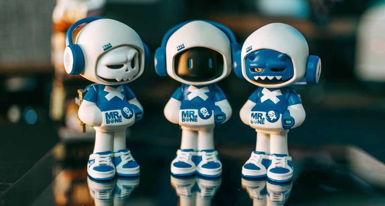 three toy figures wearing blue and white costumes with headphones labe