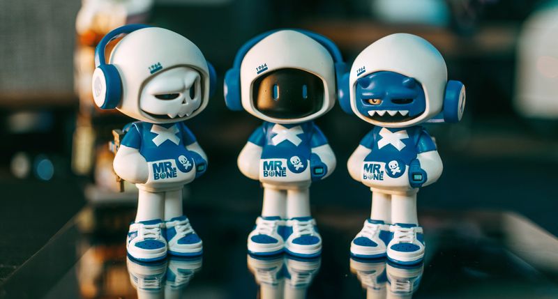 Dark-cute designer toy aesthetics showing three skeleton figure collectibles in colorful outfits on display