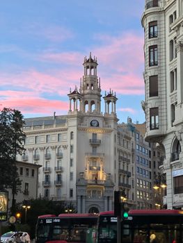 Historic building with unique towers in València during a vibrant sunset, capturing city life and architecture.