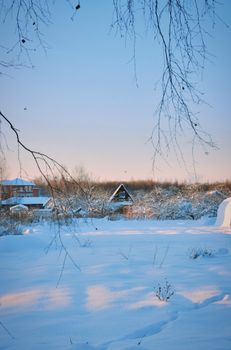 Serene winter scene with snow-covered rural houses at sunrise.