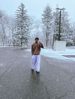 Young man in casual attire walking on snow-dusted pavement in Hackettstown, NJ.