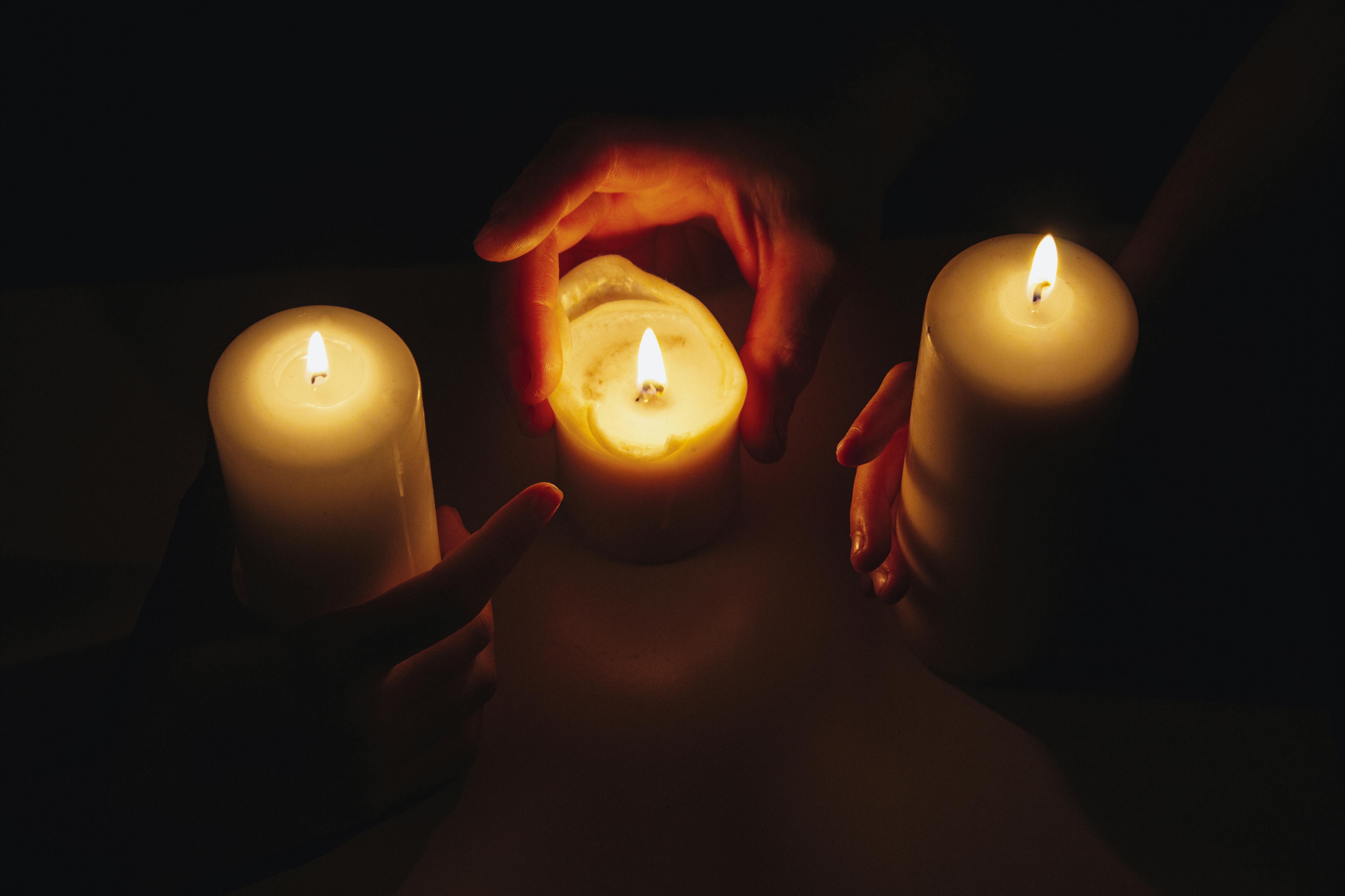 bezplatná Ruce držící hořící svíčky v intimním, meditativním světle svíček. Základová fotografie