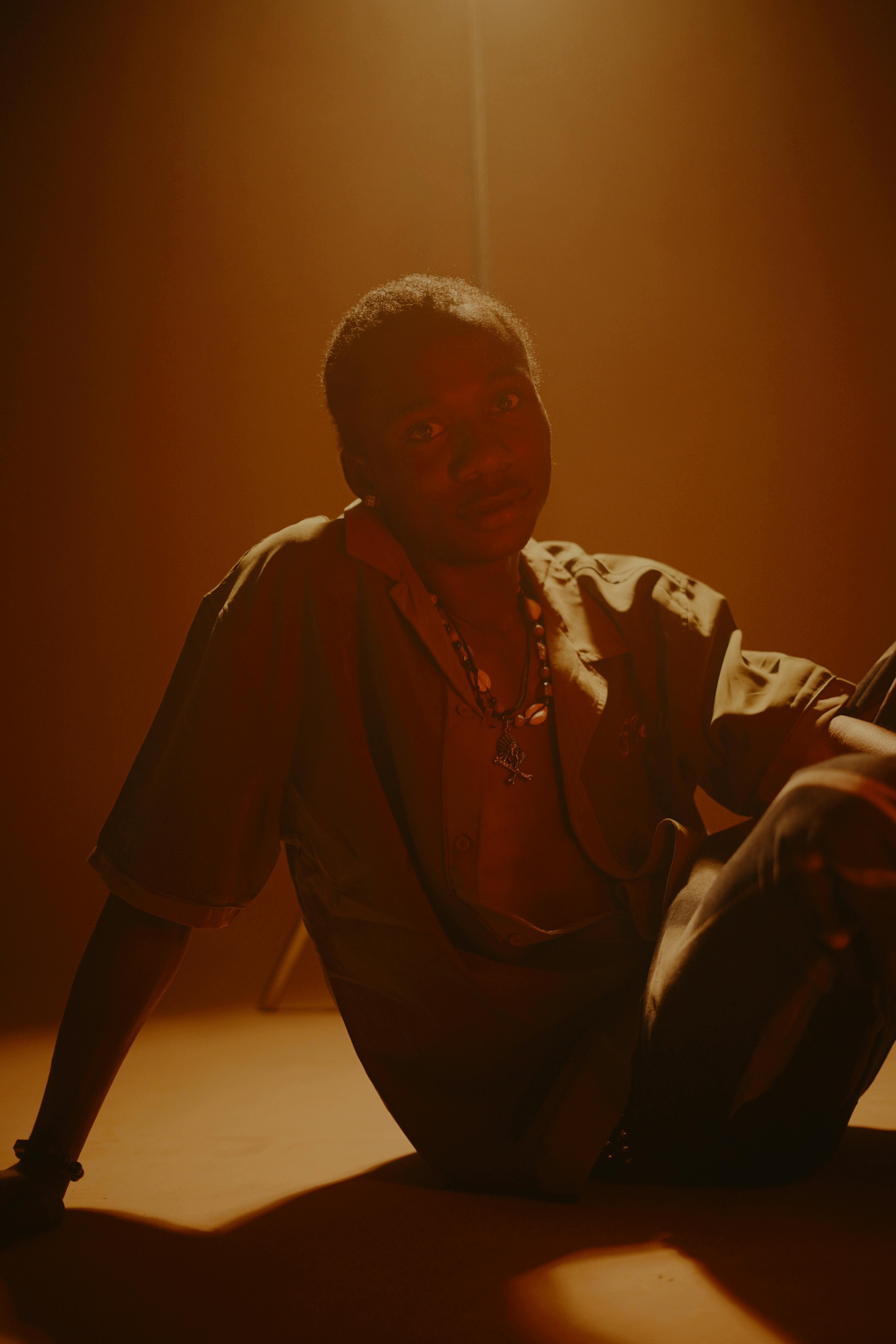 ฟรี ภาพถ่ายอันทรงพลังของชายคนหนึ่งที่นั่งอย่างสงบโดยมีฉากหลังเป็นสีโทนอบอุ่นและนุ่มนวล คลังภาพถ่าย