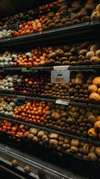 Colorful assortment of fruits and vegetables in a market setting with a price tag highlighting a kiwi offer.