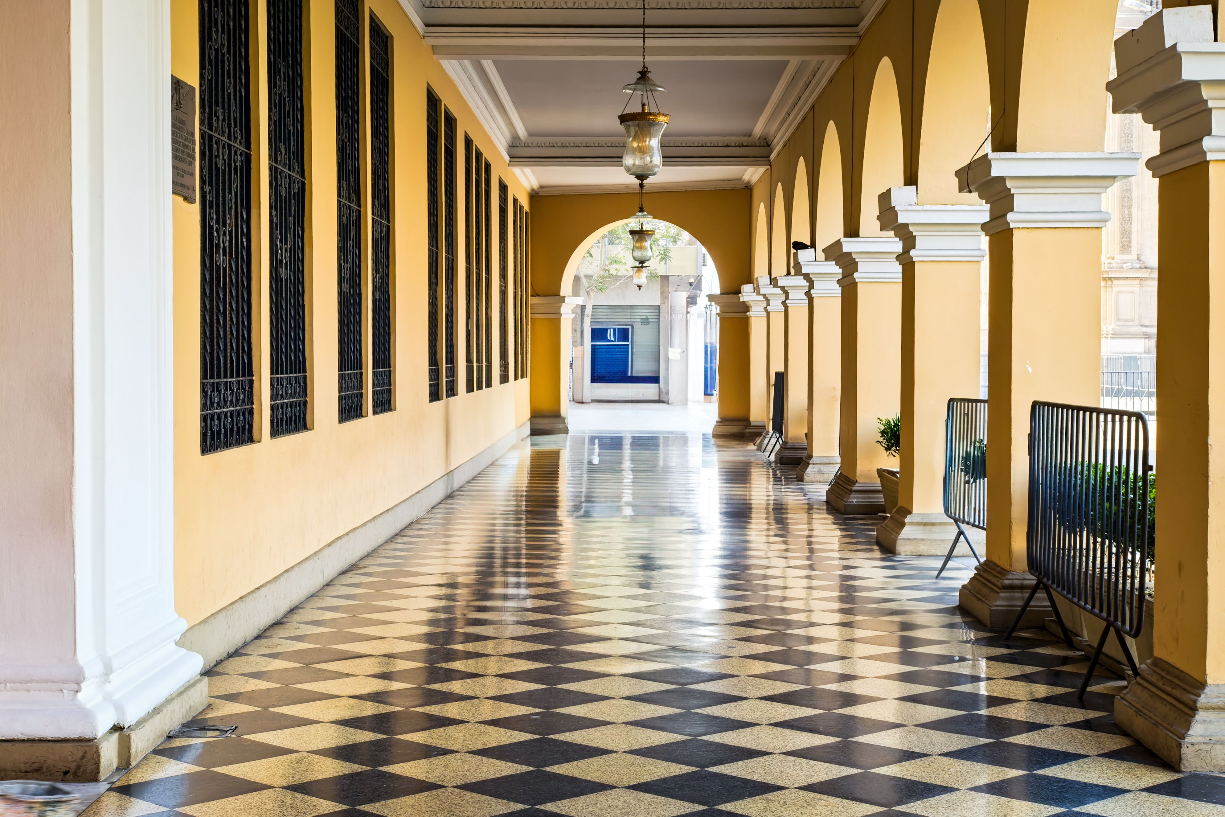 A scenic colonial-style corridor with checkered tiles and elegant arches, offering a timeless architectural view.