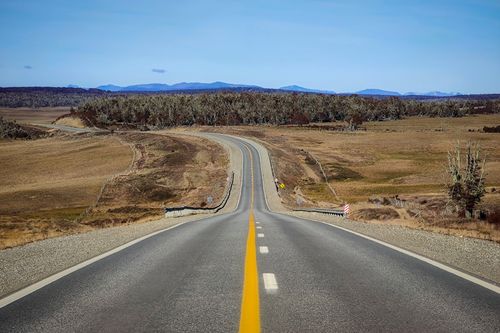 Free A long, empty road stretches into the distance through a vast, rural landscape. Stock Photo