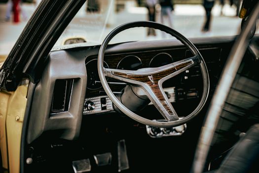Close-up of a vintage car's interior featuring a classic wooden steering wheel, evoking nostalgia.