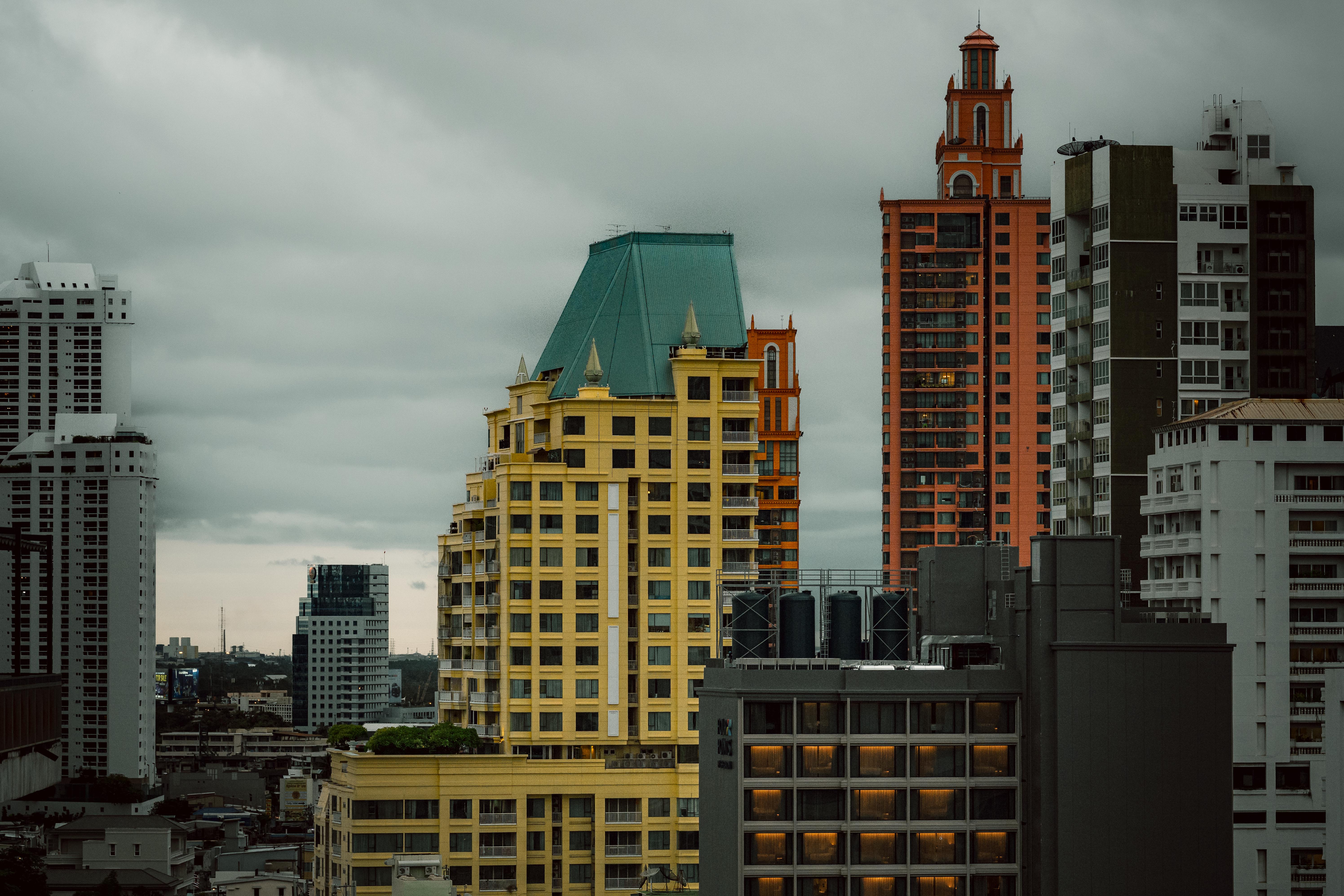 Ücretsiz Bangkok'un silüetinin çarpıcı bir görüntüsü; kasvetli bir gökyüzüne karşı kendine özgü renkli binalar sergiliyor. Stok Fotoğraflar