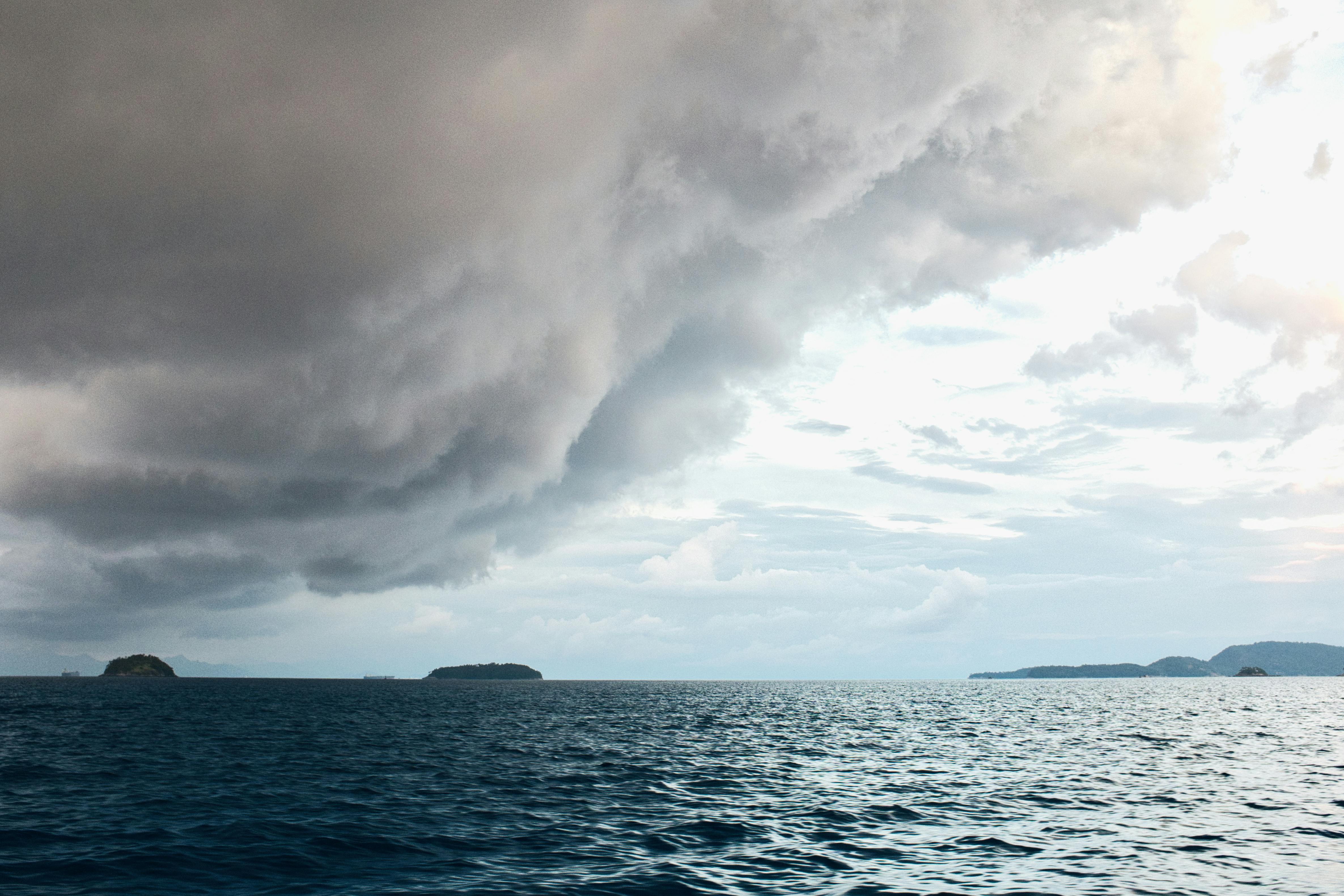 A dramatic storm cloud looms over a calm ocean, highlighting nature's power and serenity.