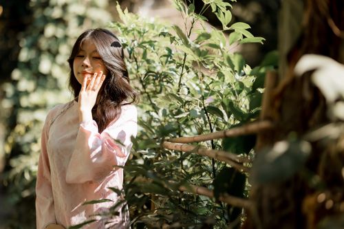 Free A young woman enjoys the sunlight in a lush green outdoor setting, embodying peace and nature. Stock Photo