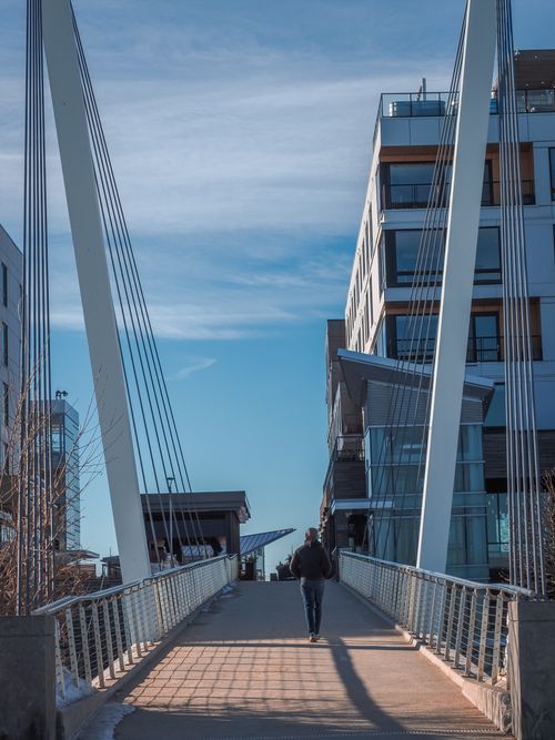 Free A lone person walks across a modern bridge in Revere, MA under a blue sky. Stock Photo