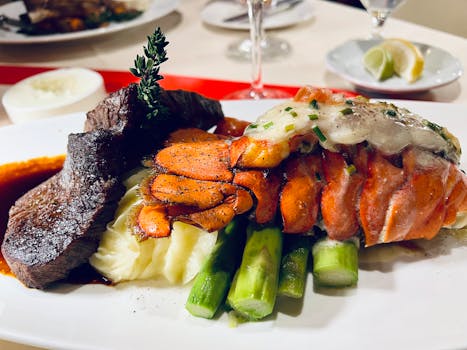 Indulge in a luxurious surf and turf meal featuring lobster tail, steak, and asparagus.