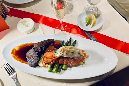 Elegant surf and turf dinner featuring steak, lobster, and asparagus, paired with champagne.