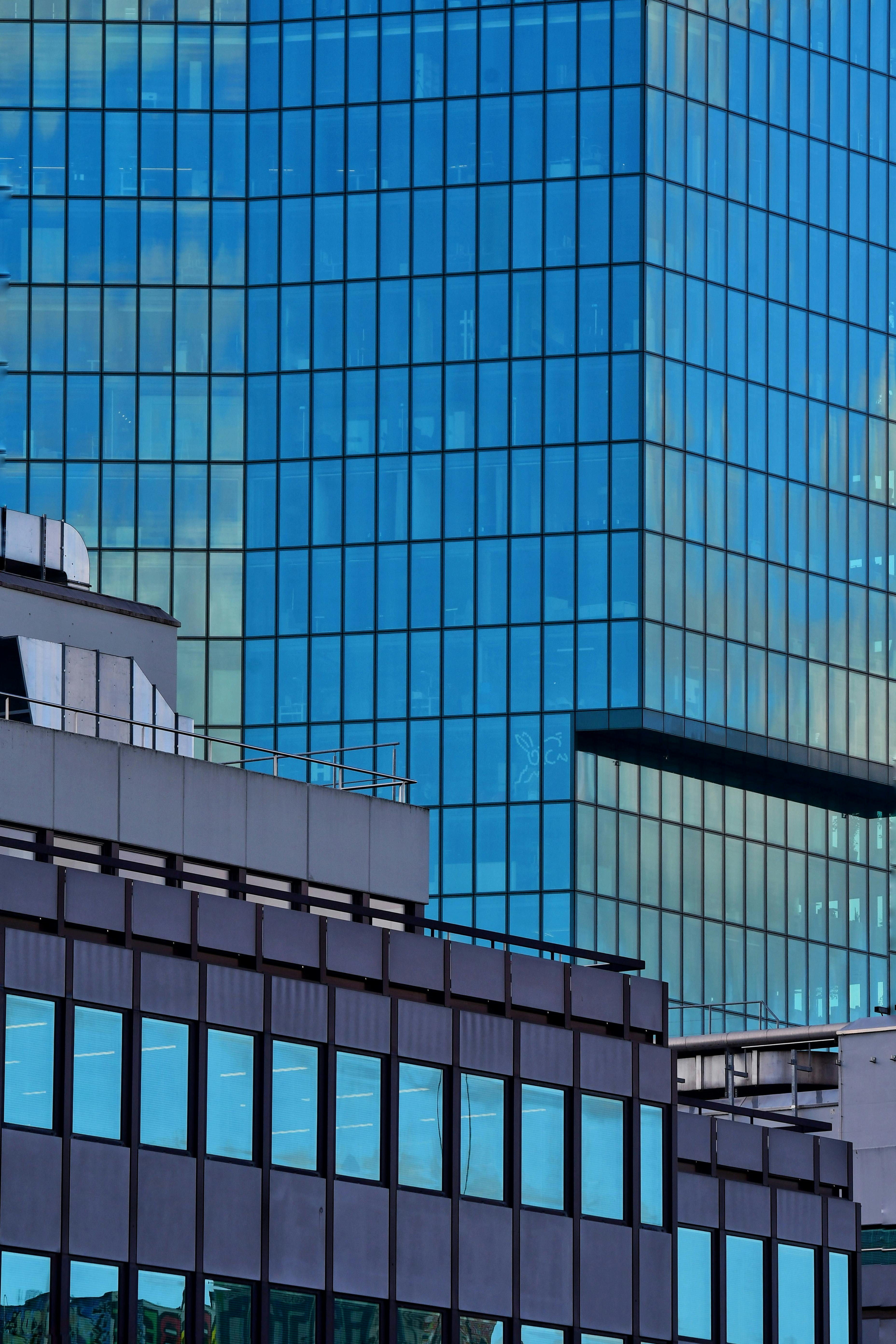 Gratis Nærbilde av en moderne glassfasade på en skyskraper i et travelt bymiljø. Arkivbilde