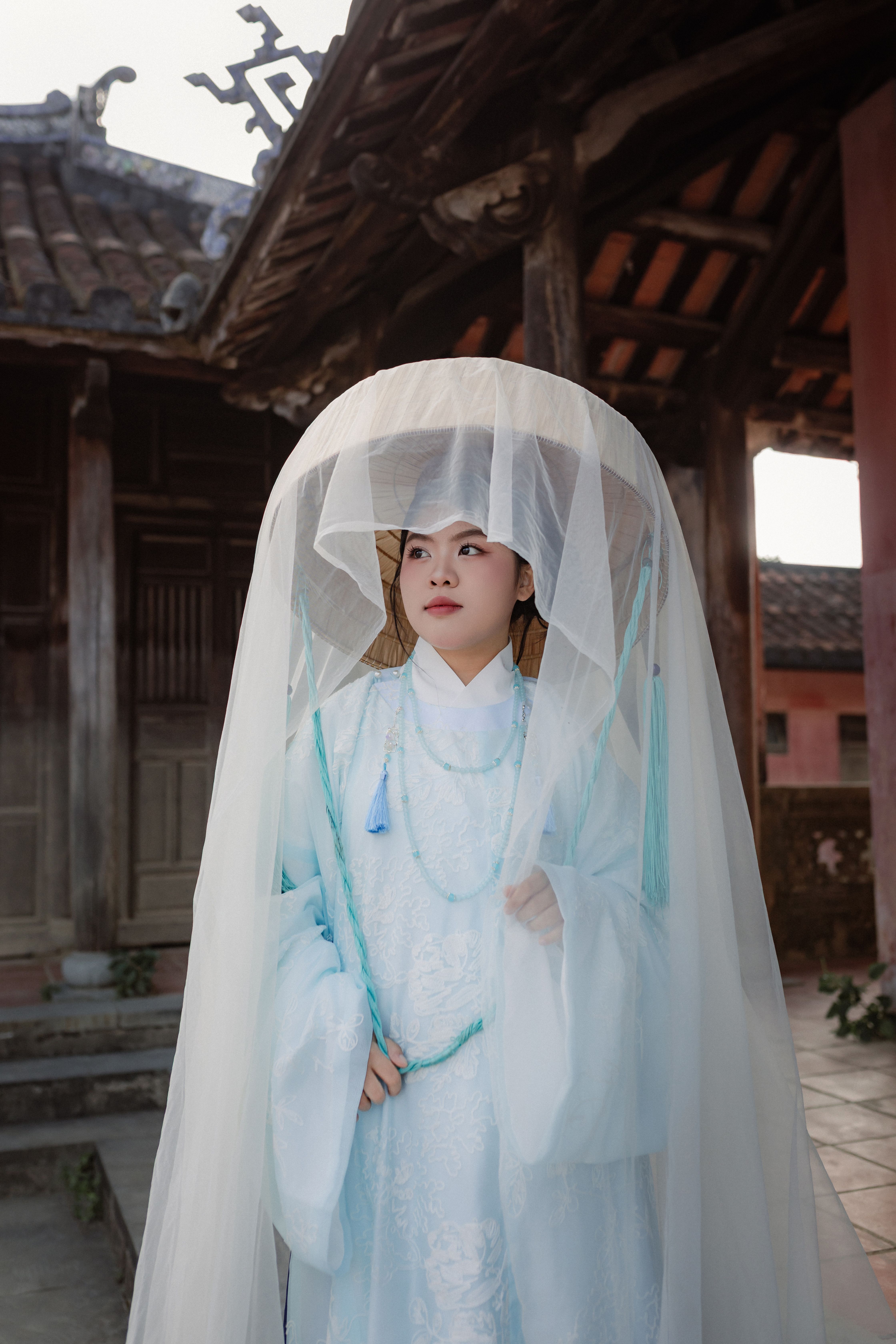 A woman in traditional Vietnamese attire poses at a historic site in Hội An.