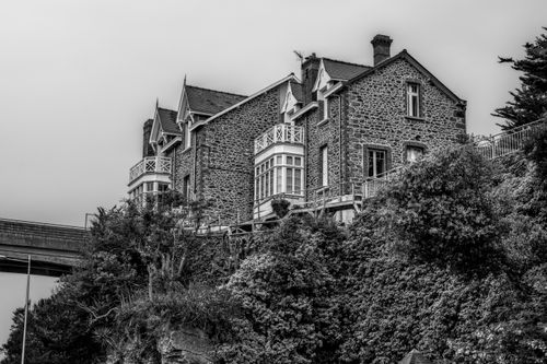 Free Black and white image of a historic stone house with lush foliage in Brittany. Stock Photo