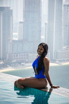 Woman enjoys infinity pool with breathtaking urban skyline backdrop.
